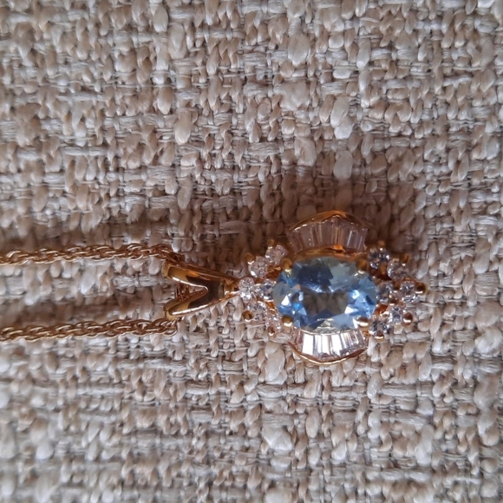 Gold necklace with aqua stone and clear stones and baguettes.
